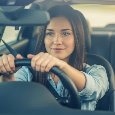 A woman driving with both hands on the wheel